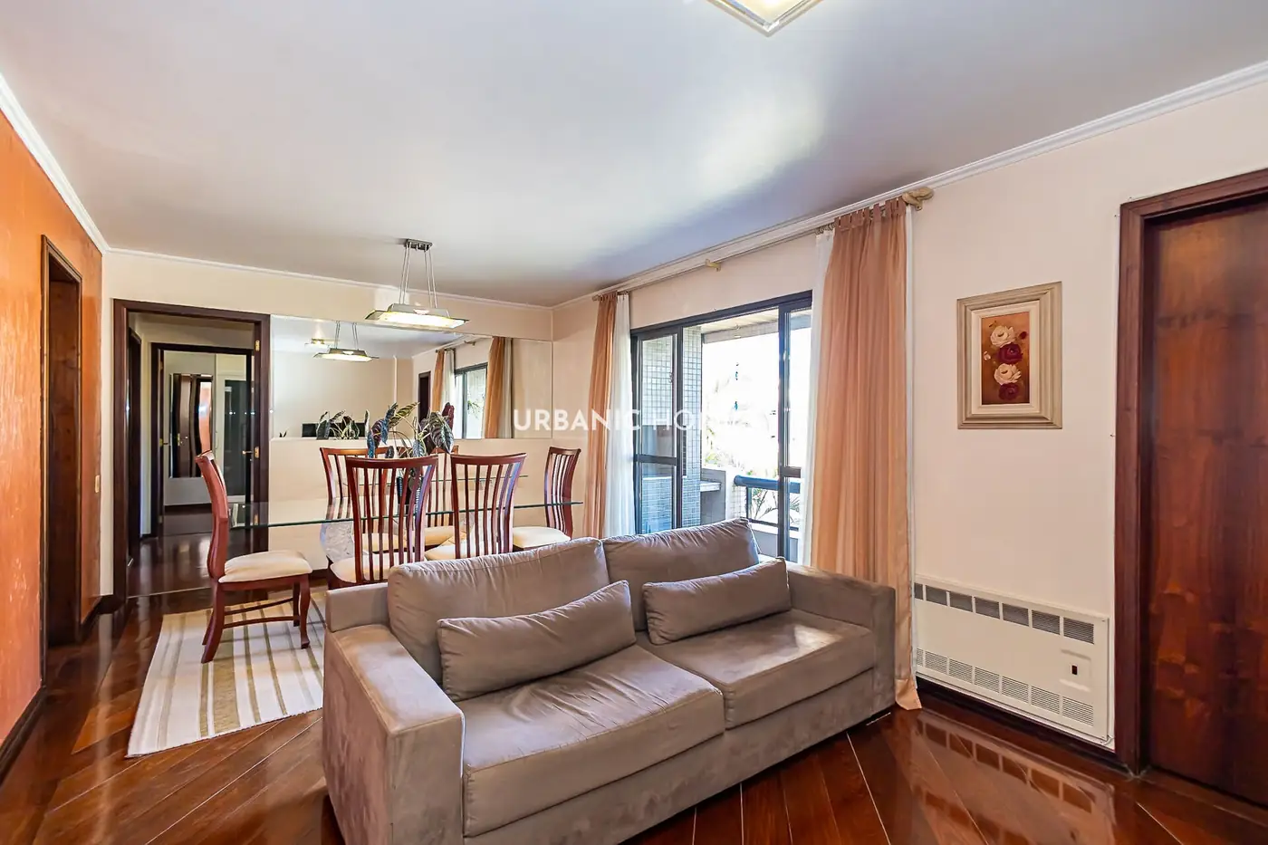 Sala de estar com piso de madeira e o jantar ao fundo