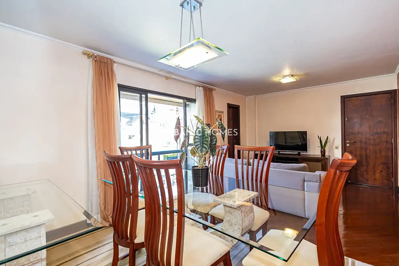 Mesa de jantar de vidro com a sala ao fundo